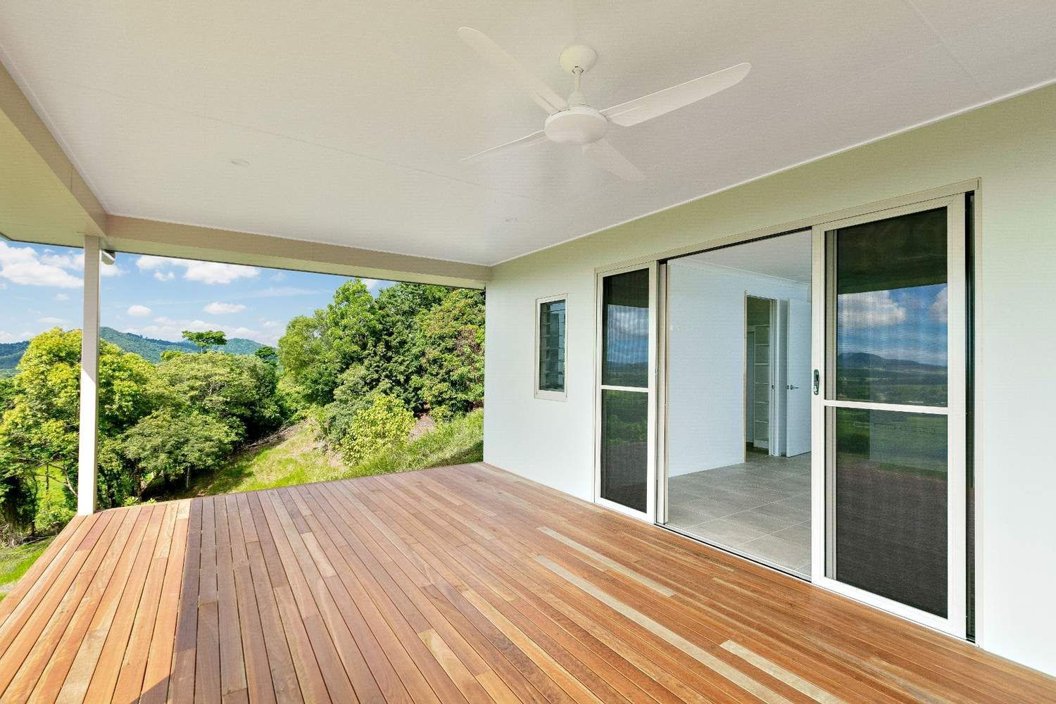 An Empty Deck With a Ceiling Fan and Sliding Glass Doors — Ashlee Jones Homes in Gordonvale, QLD