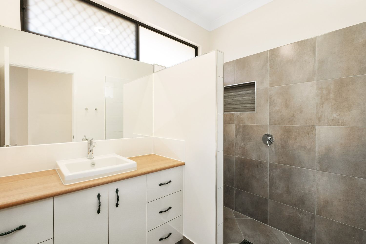 A Bathroom With a Sink, Mirror and Shower — Ashlee Jones Homes in Gordonvale, QLD