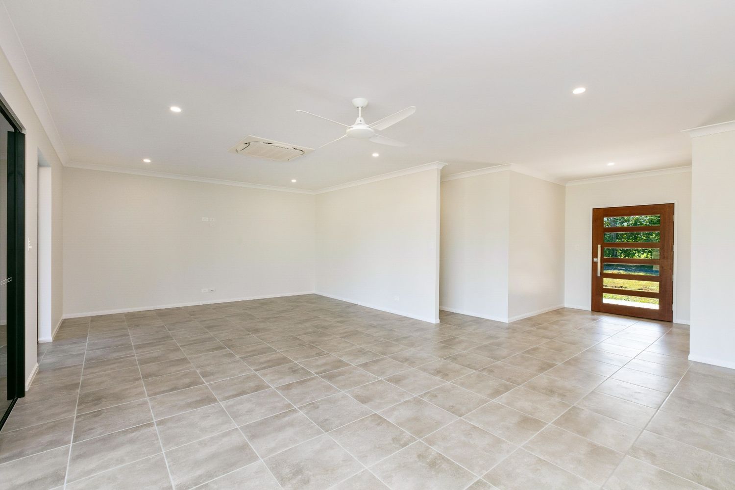 An Empty Living Room With Tile Floors and a Ceiling Fan — Ashlee Jones Homes in Gordonvale, QLD