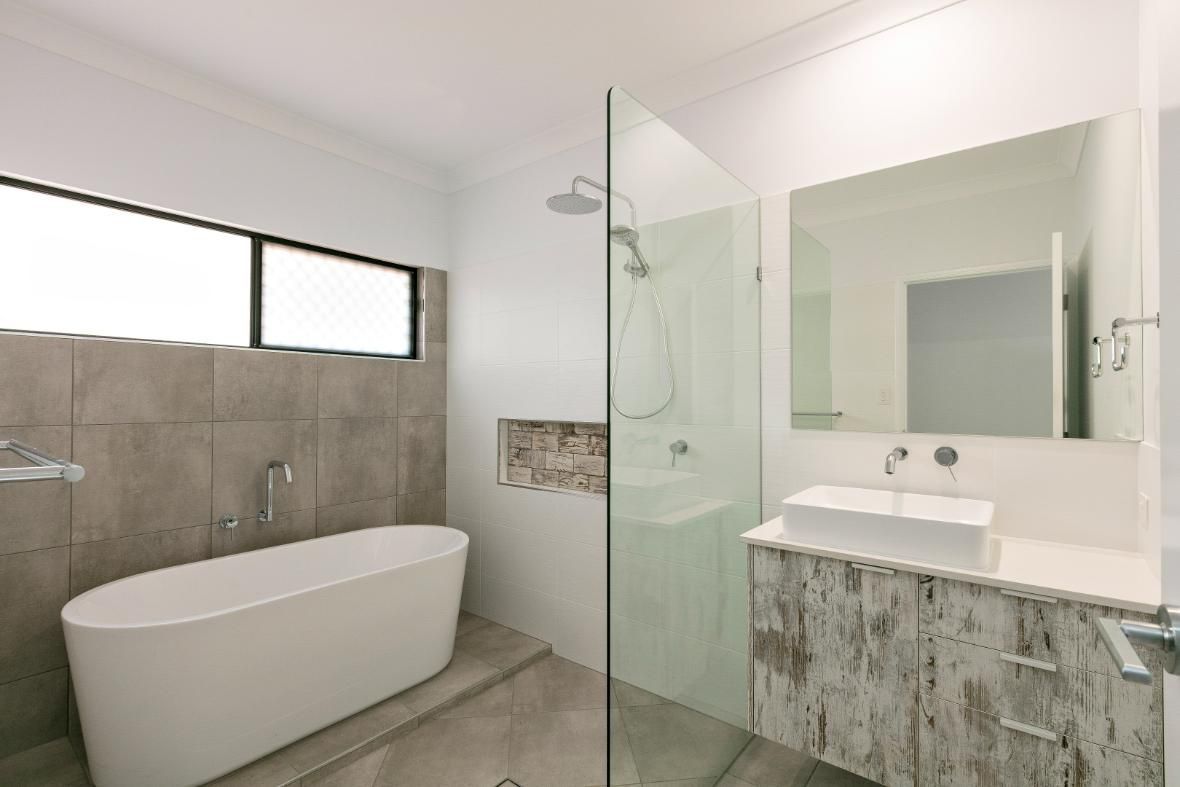 A Bathroom With a Bathtub, Sink , Shower and Mirror — Ashlee Jones Homes in Gordonvale, QLD
