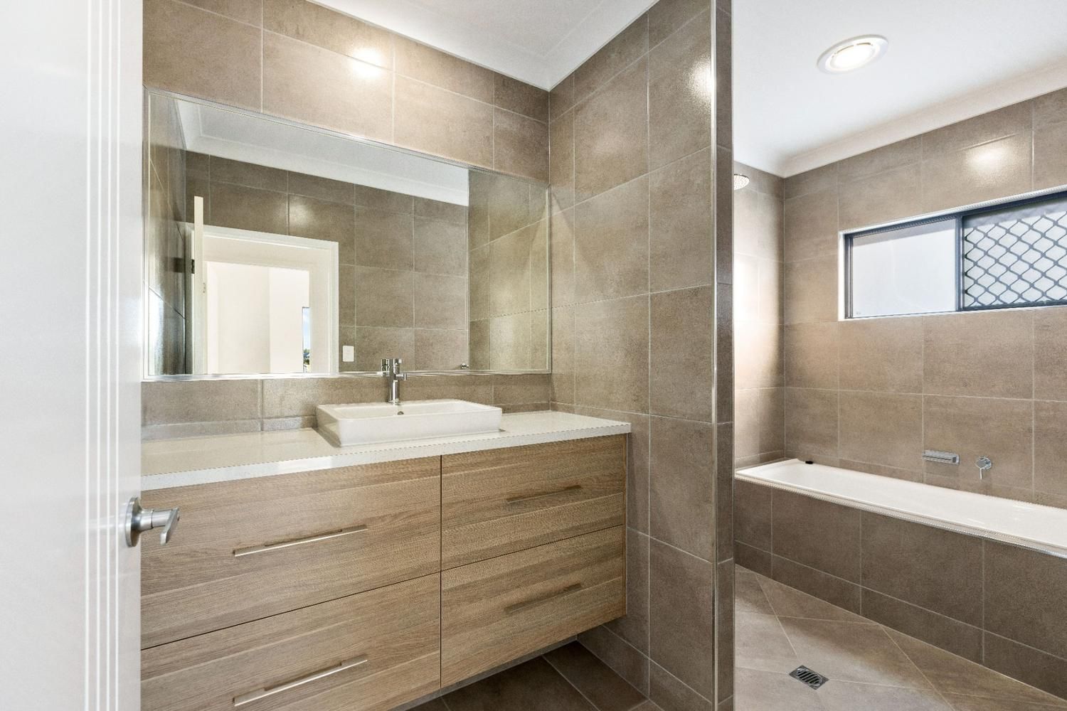 A Bathroom With a Sink, Mirror and Bathtub — Ashlee Jones Homes in Gordonvale, QLD