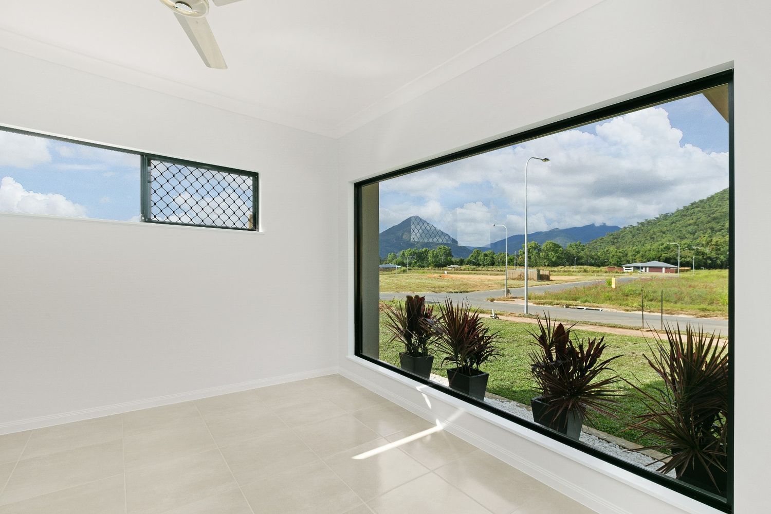 An Empty Room With a Large Window Looking Out to a Field — Ashlee Jones Homes in Gordonvale, QLD