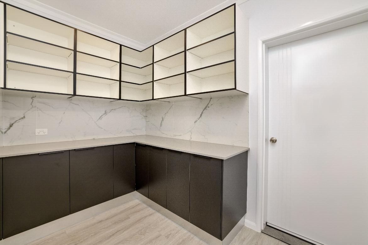 A Kitchen With Black Cabinets and White Counter Tops and a White Door — Ashlee Jones Homes in Gordonvale, QLD