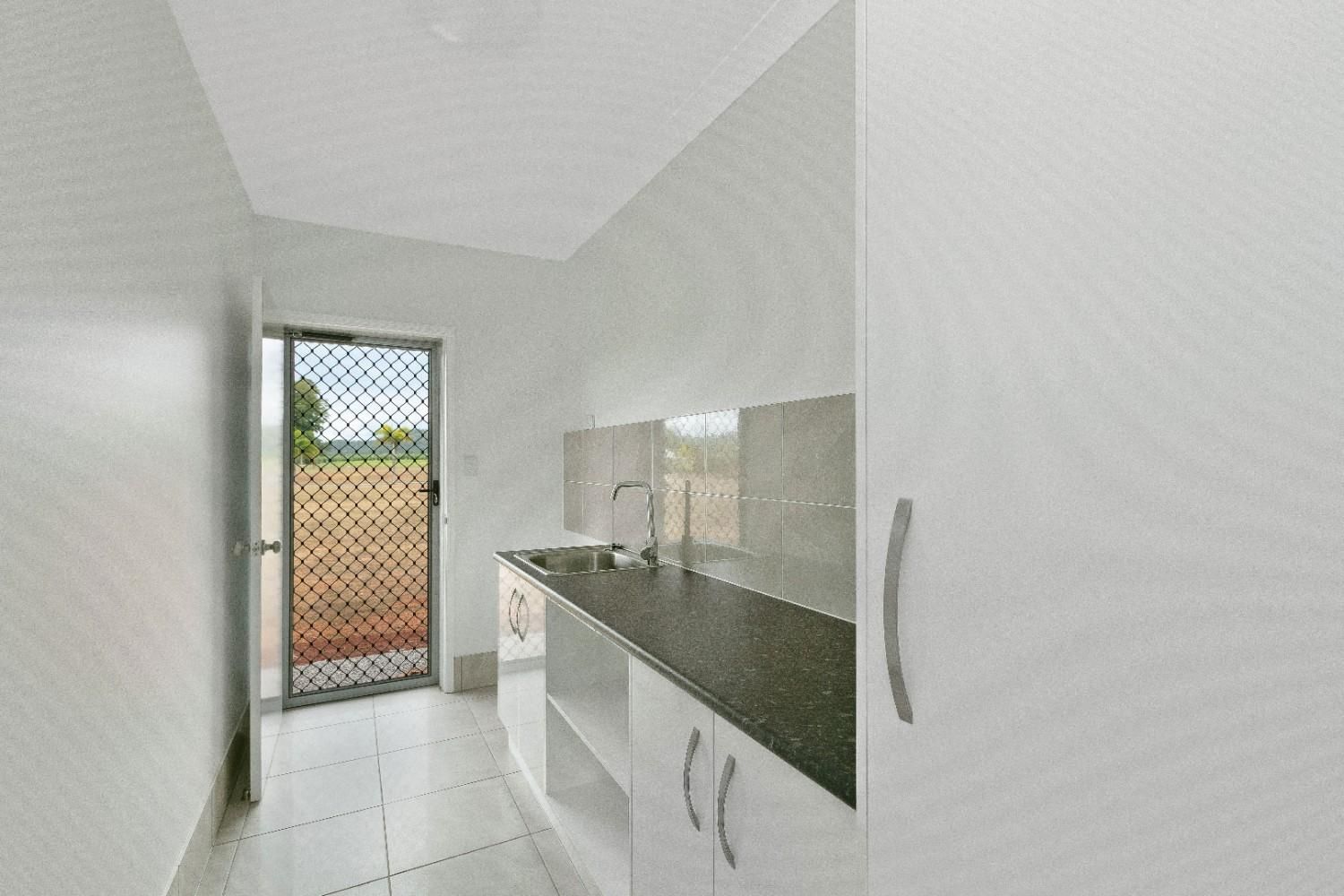 A Kitchen With White Cabinets and a Black Counter Top — Ashlee Jones Homes in Gordonvale, QLD