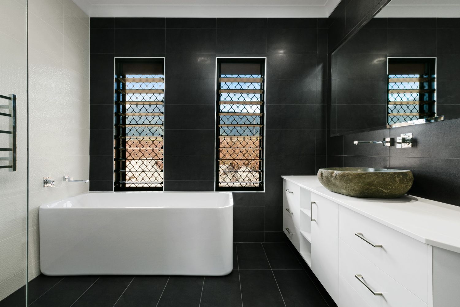 A Bathroom With a Bathtub, Sink and Mirror — Ashlee Jones Homes in Gordonvale, QLD