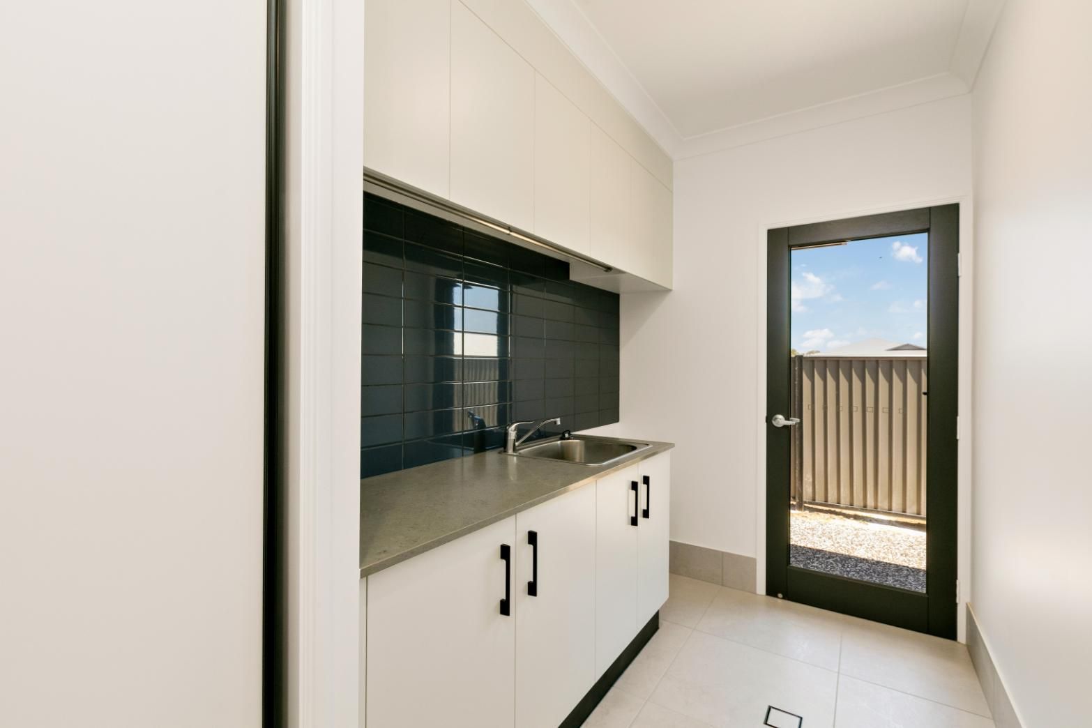 A Kitchen With White Cabinets, a Sink, and a Door — Ashlee Jones Homes in Gordonvale, QLD
