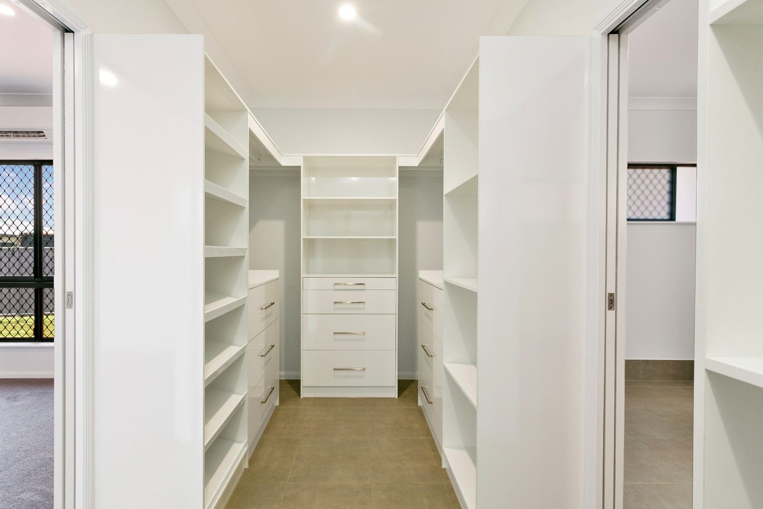 A Walk in Closet With Lots of Shelves and Drawers in a House — Ashlee Jones Homes in Gordonvale, QLD