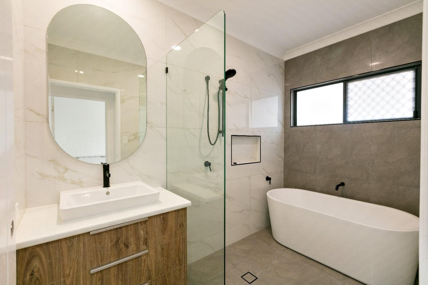A Bathroom With a Bathtub, Sink, Shower and Mirror — Ashlee Jones Homes in Gordonvale, QLD