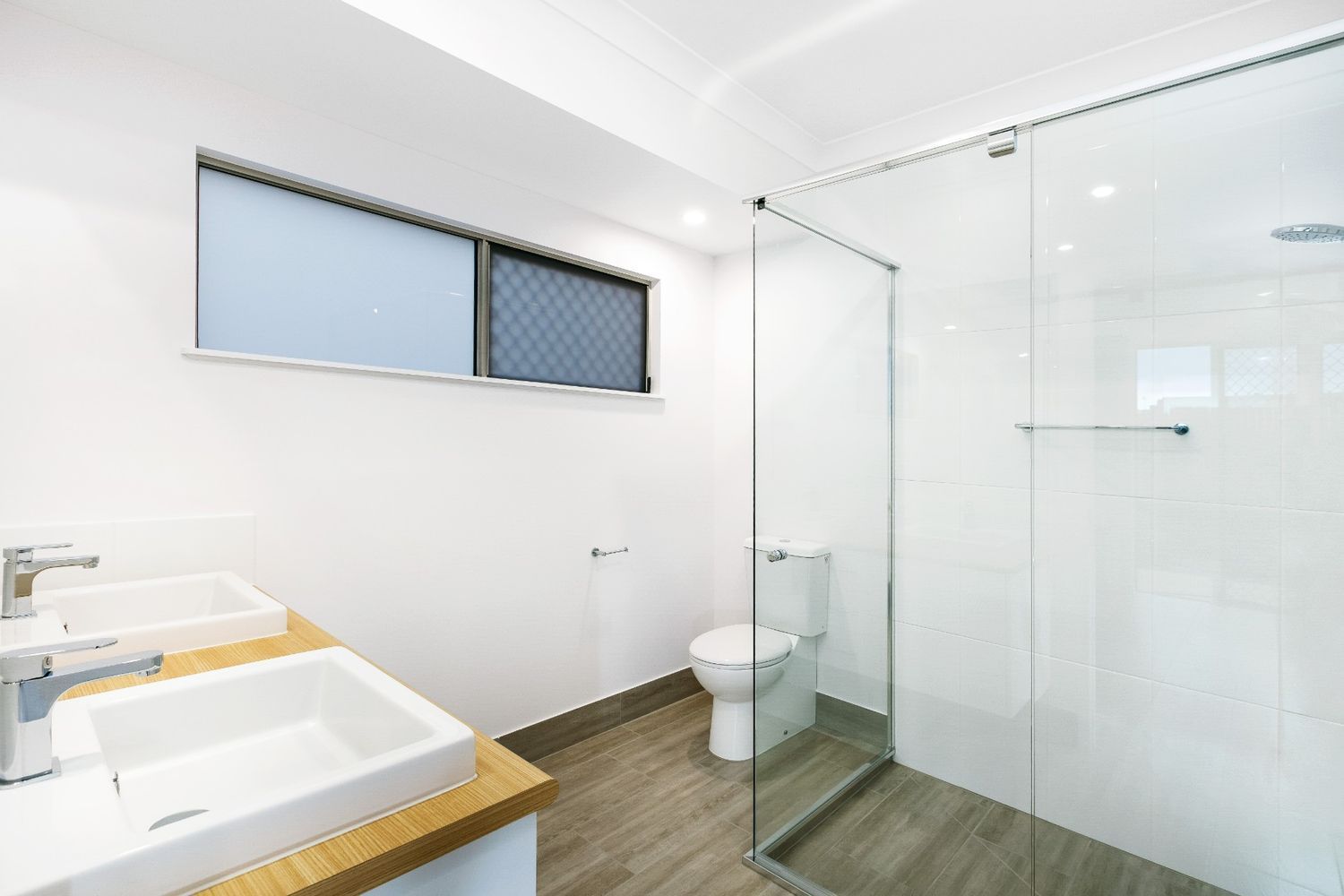 A Bathroom With Two Sinks, a Toilet and a Walk in Shower — Ashlee Jones Homes in Gordonvale, QLD