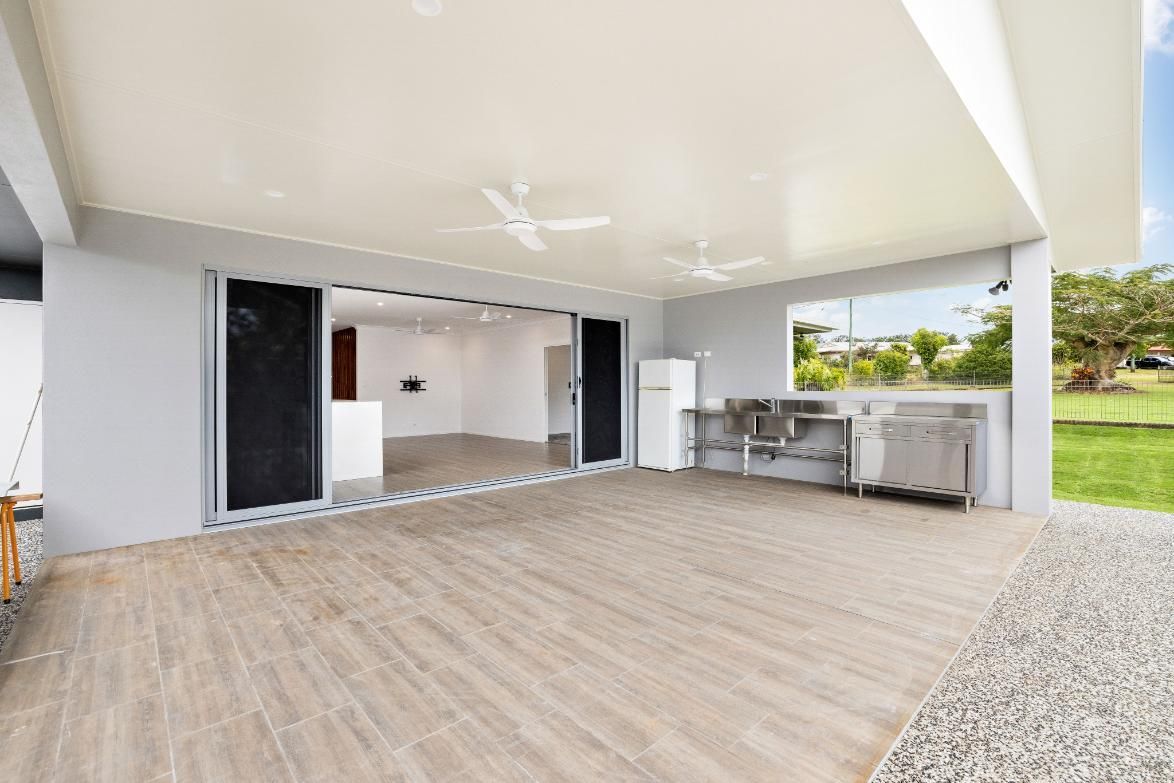 A Large Patio With Sliding Glass Doors and a Kitchen in the Background — Ashlee Jones Homes in Gordonvale, QLD