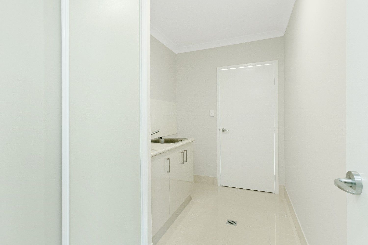 A Laundry Room With White Cabinets, a Sink and a Door — Ashlee Jones Homes in Gordonvale, QLD