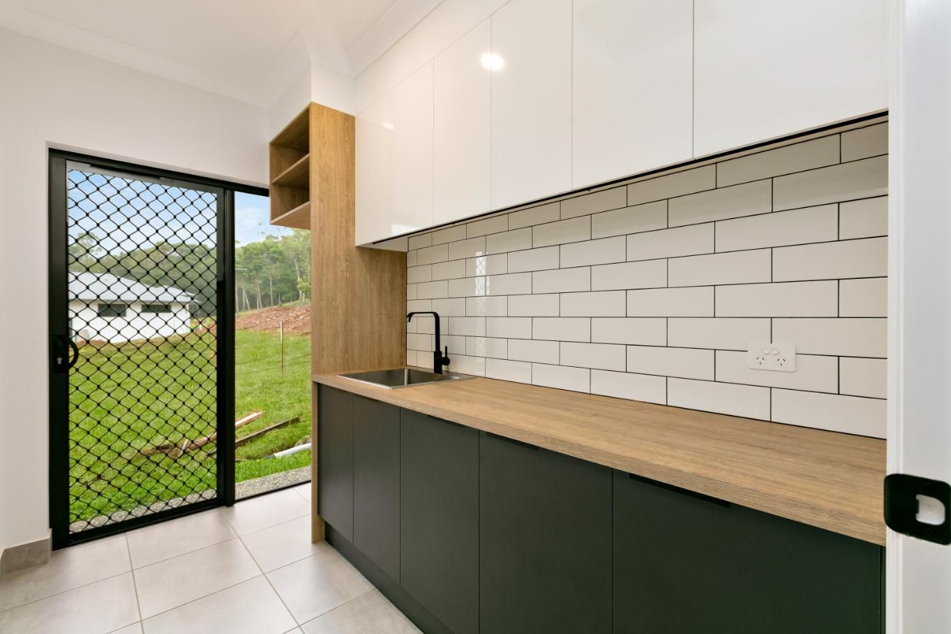 A Kitchen With a Sink, Cabinets, and a Sliding Glass Door — Ashlee Jones Homes in Gordonvale, QLD