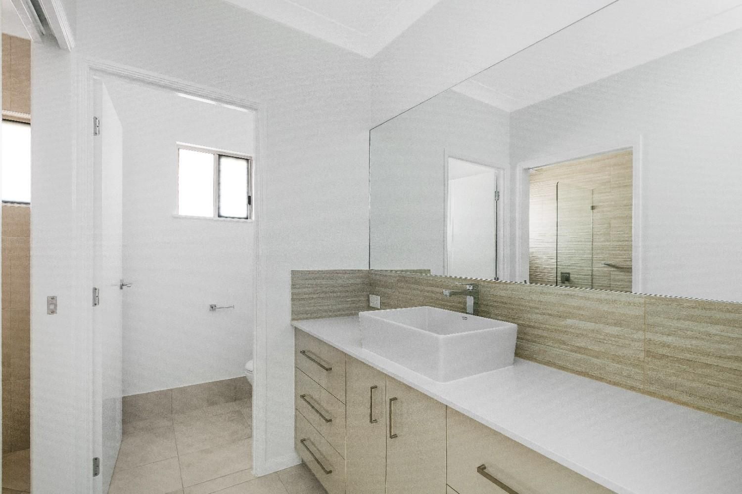 A Bathroom With a Sink, Mirror and Cabinets — Ashlee Jones Homes in Gordonvale, QLD