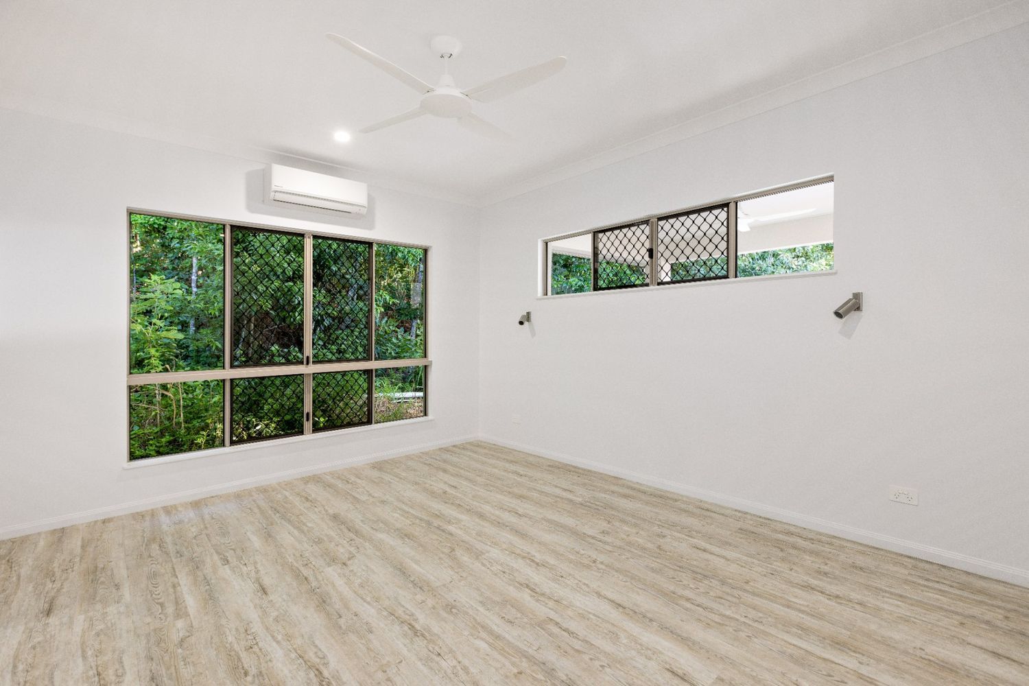 An Empty Room With a Wooden Floor and a Ceiling Fan — Ashlee Jones Homes in Gordonvale, QLD