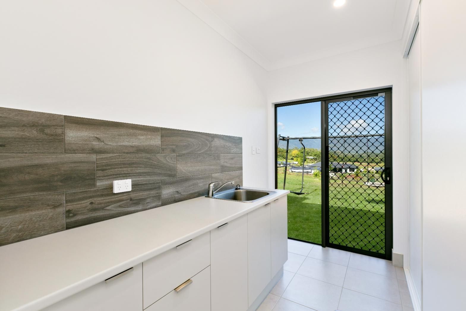 A Kitchen With a Sink and a Sliding Glass Door — Ashlee Jones Homes in Gordonvale, QLD