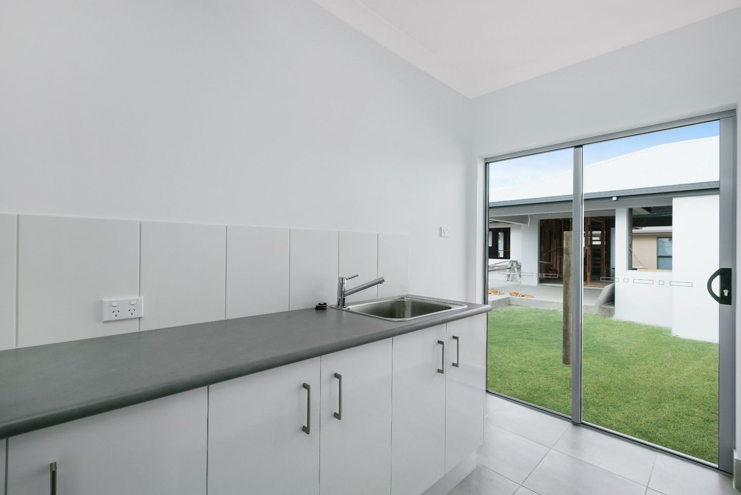 A Kitchen With a Sink and a Sliding Glass Door — Ashlee Jones Homes in Gordonvale, QLD