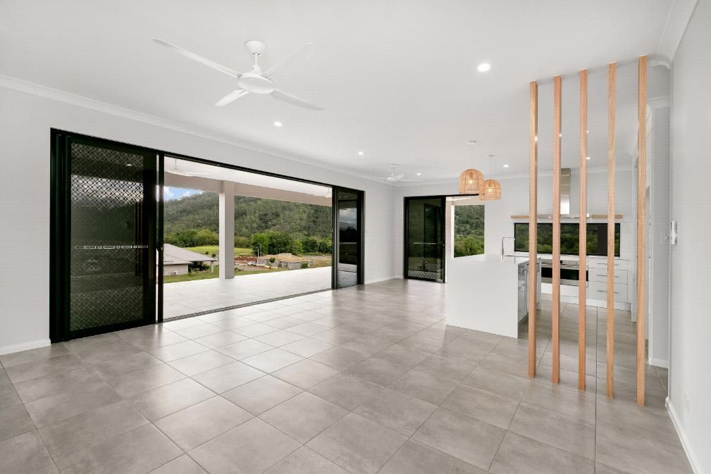 An Empty Living Room With a Ceiling Fan and Sliding Glass Doors — Ashlee Jones Homes in Gordonvale, QLD