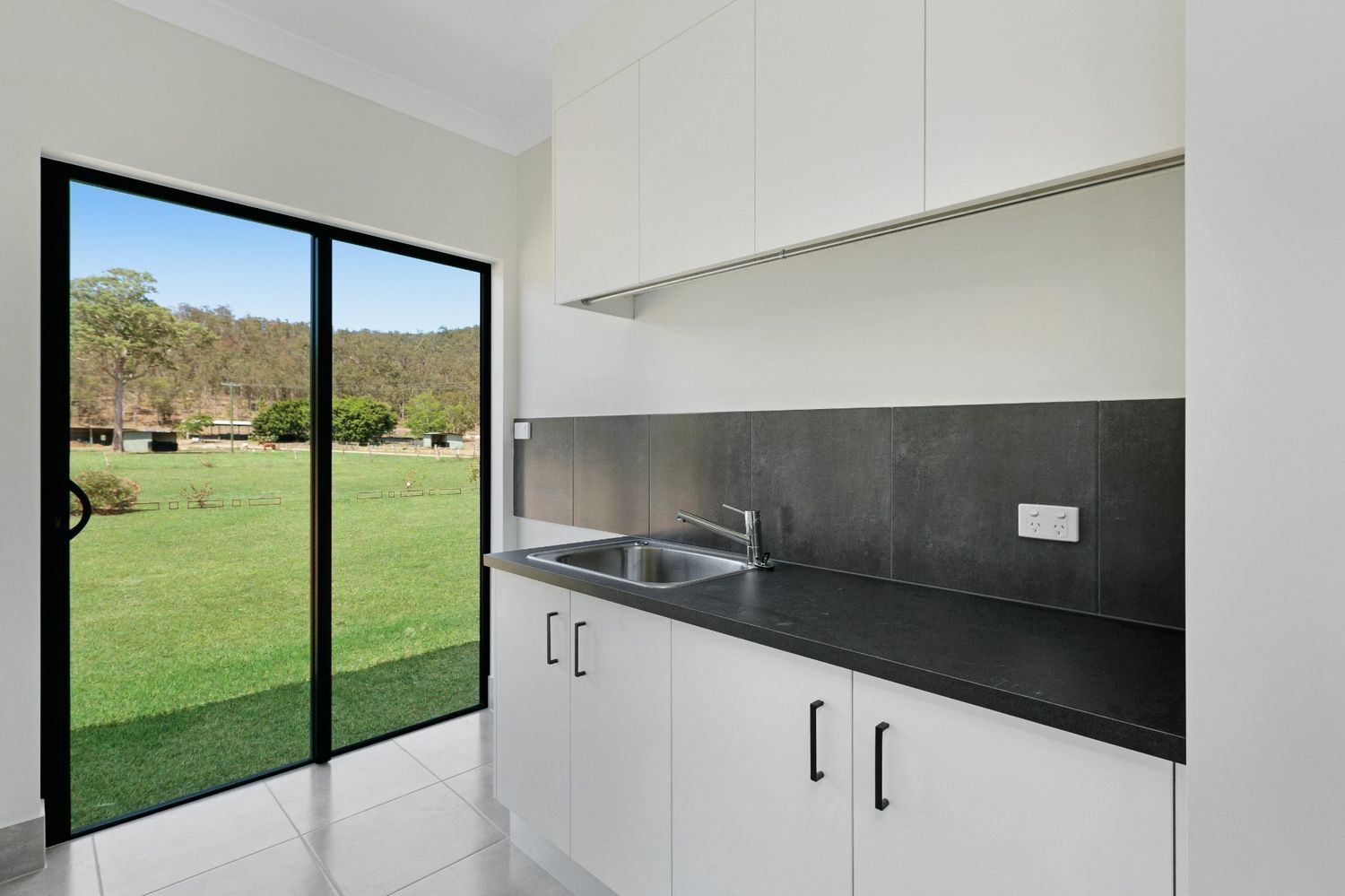 A Kitchen With a Sink and a Sliding Glass Door — Ashlee Jones Homes in Gordonvale, QLD