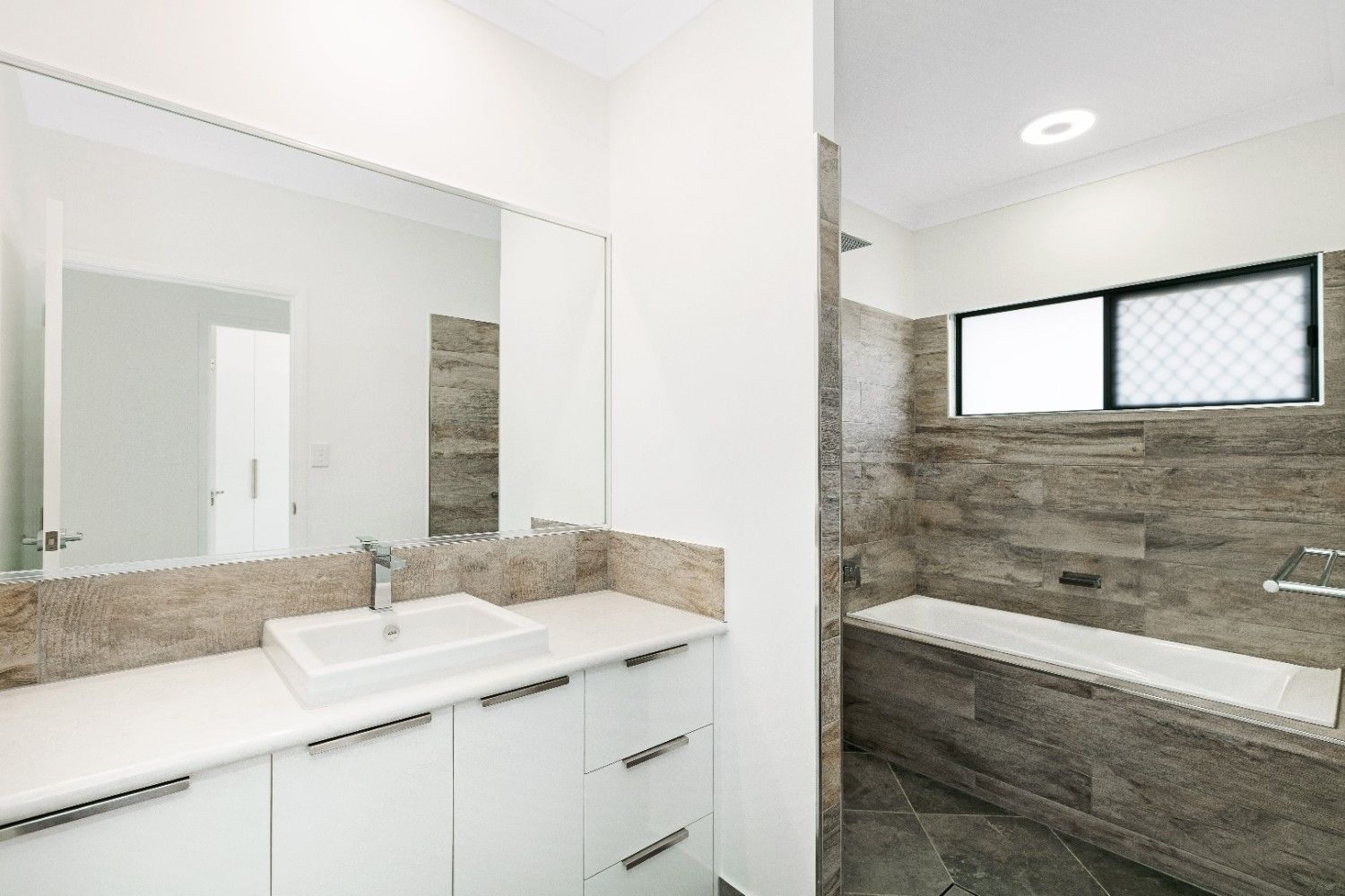 A Bathroom With a Sink, Mirror and Bathtub — Ashlee Jones Homes in Gordonvale, QLD