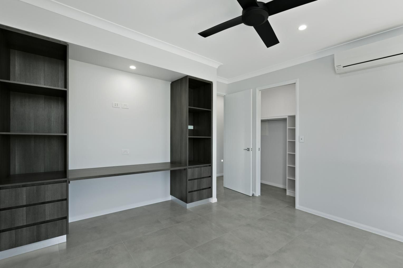 An Empty Room With a Desk, Shelves, and a Ceiling Fan — Ashlee Jones Homes in Gordonvale, QLD