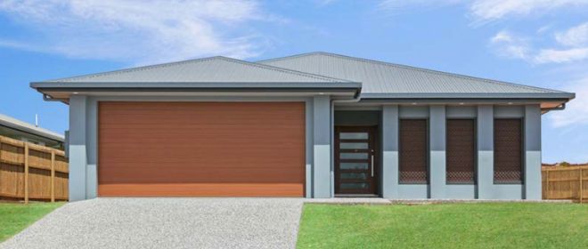 A Small House With a Garage Door and a Fence in Front of It — Ashlee Jones Homes in Gordonvale, QLD