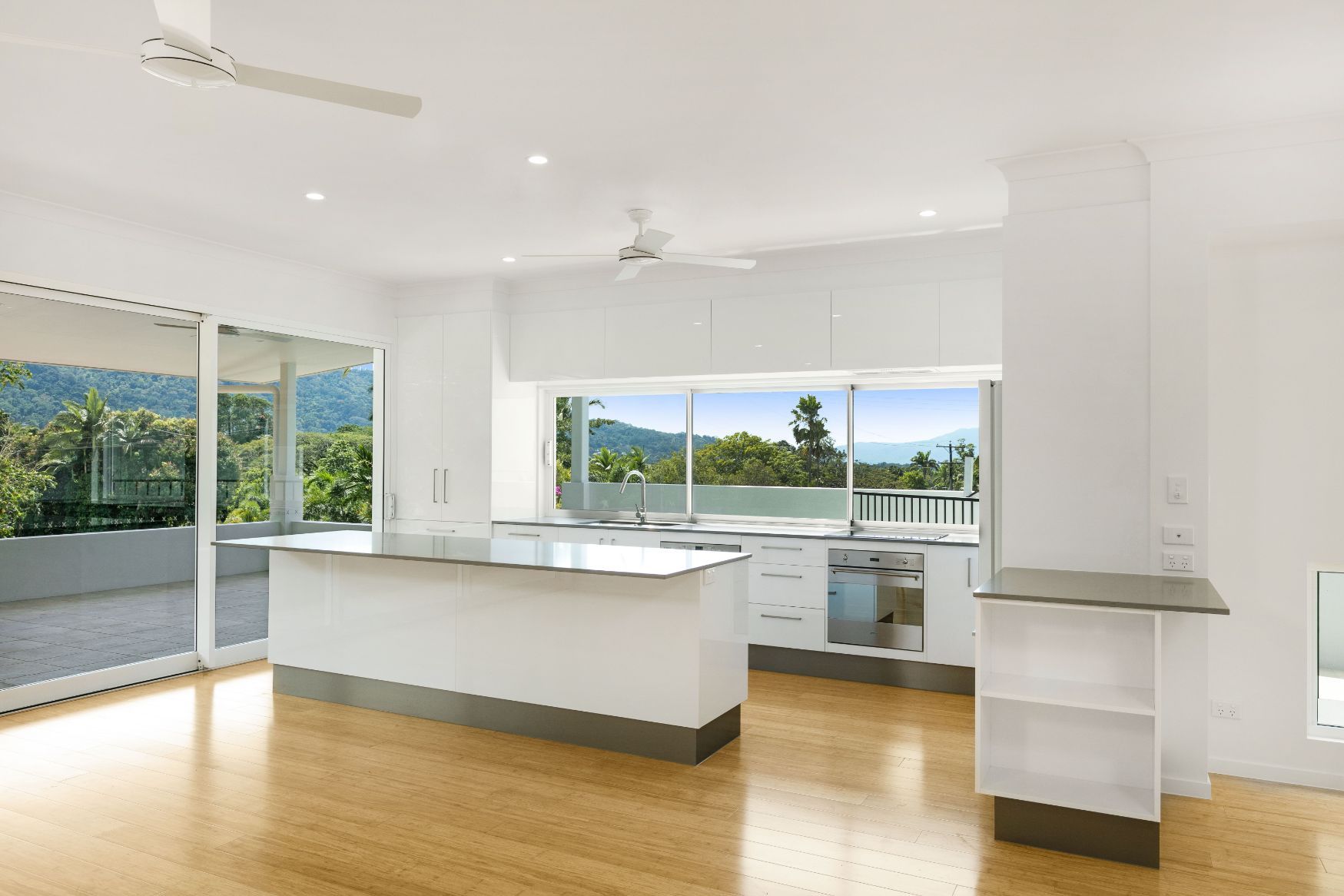 An Empty Kitchen With a Large Island and a Ceiling Fan — Ashlee Jones Homes in Gordonvale, QLD