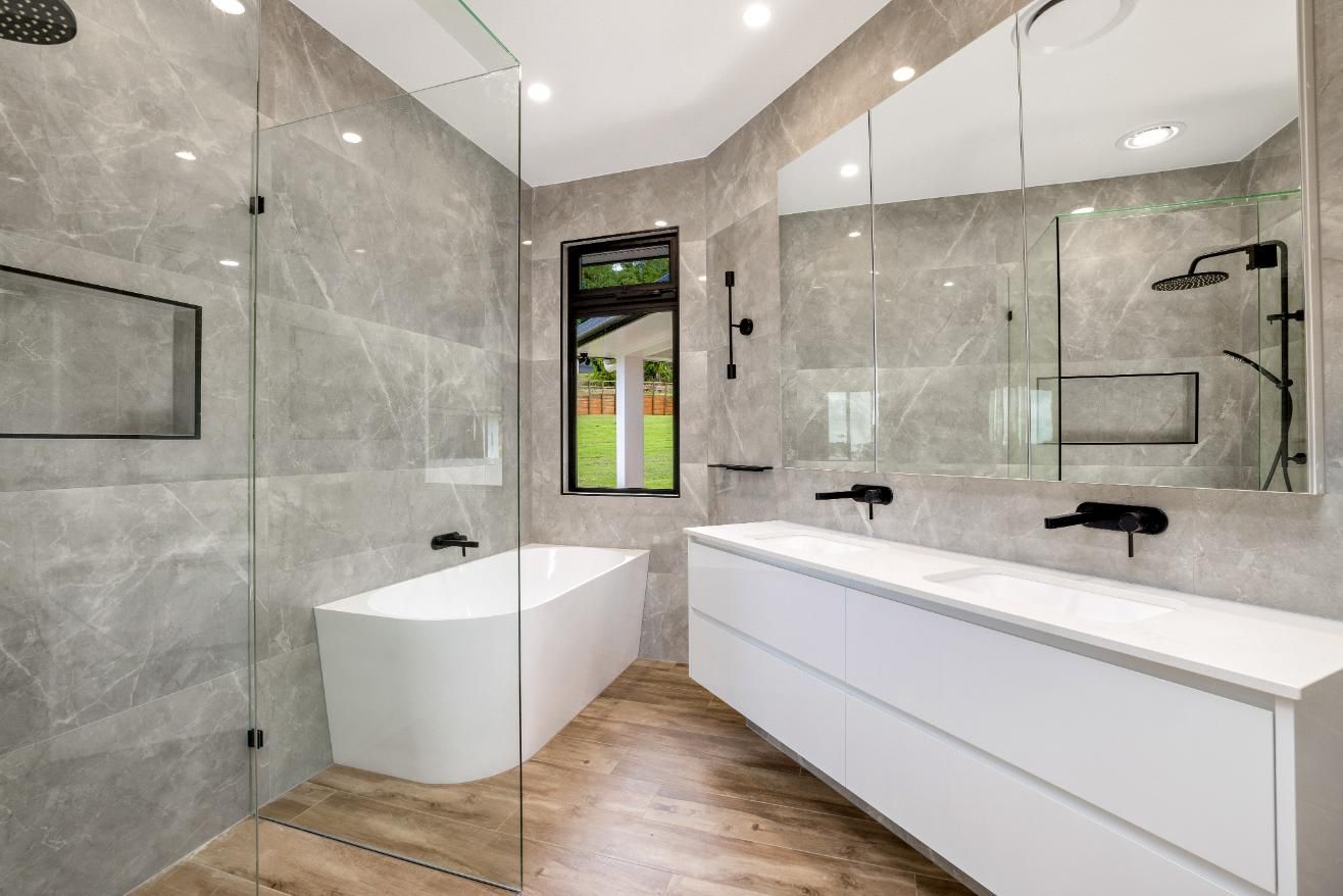 A Bathroom With a Bathtub, Sink, Mirror and Walk in Shower — Ashlee Jones Homes in Gordonvale, QLD