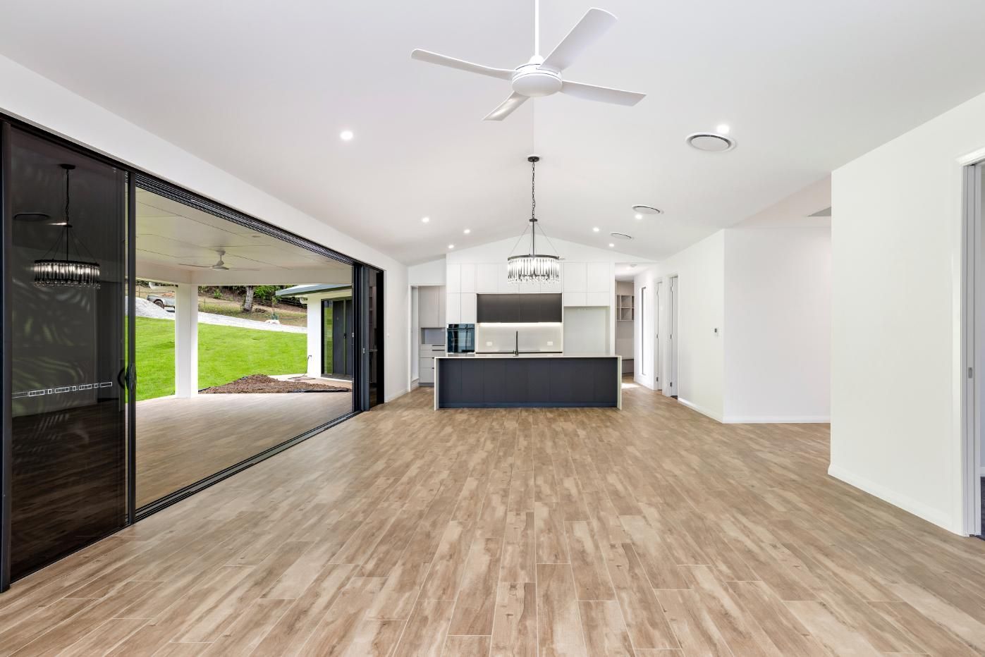 A Large Empty Room With Hardwood Floors and a Ceiling Fan — Ashlee Jones Homes in Gordonvale, QLD