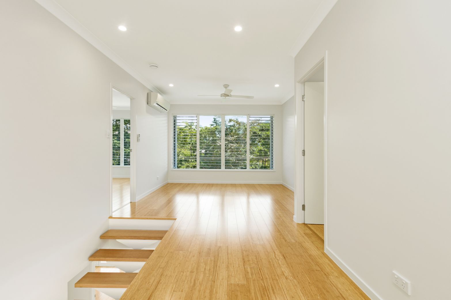 An Empty Room With Hardwood Floors and White Walls — Ashlee Jones Homes in Gordonvale, QLD