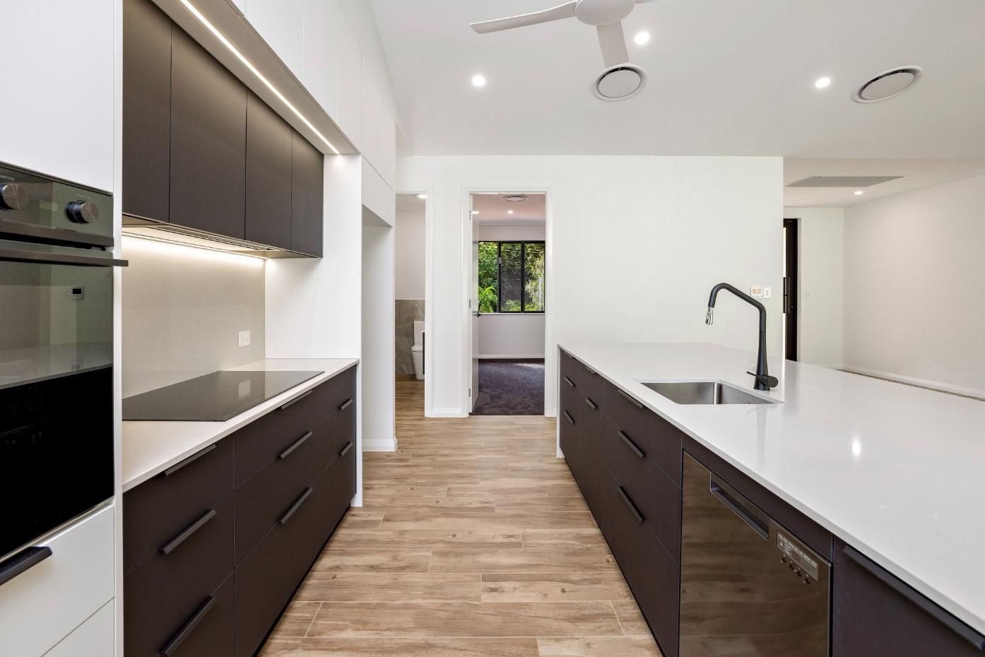 A Kitchen With Black Cabinets and White Counter Tops and a Ceiling Fan — Ashlee Jones Homes in Gordonvale, QLD