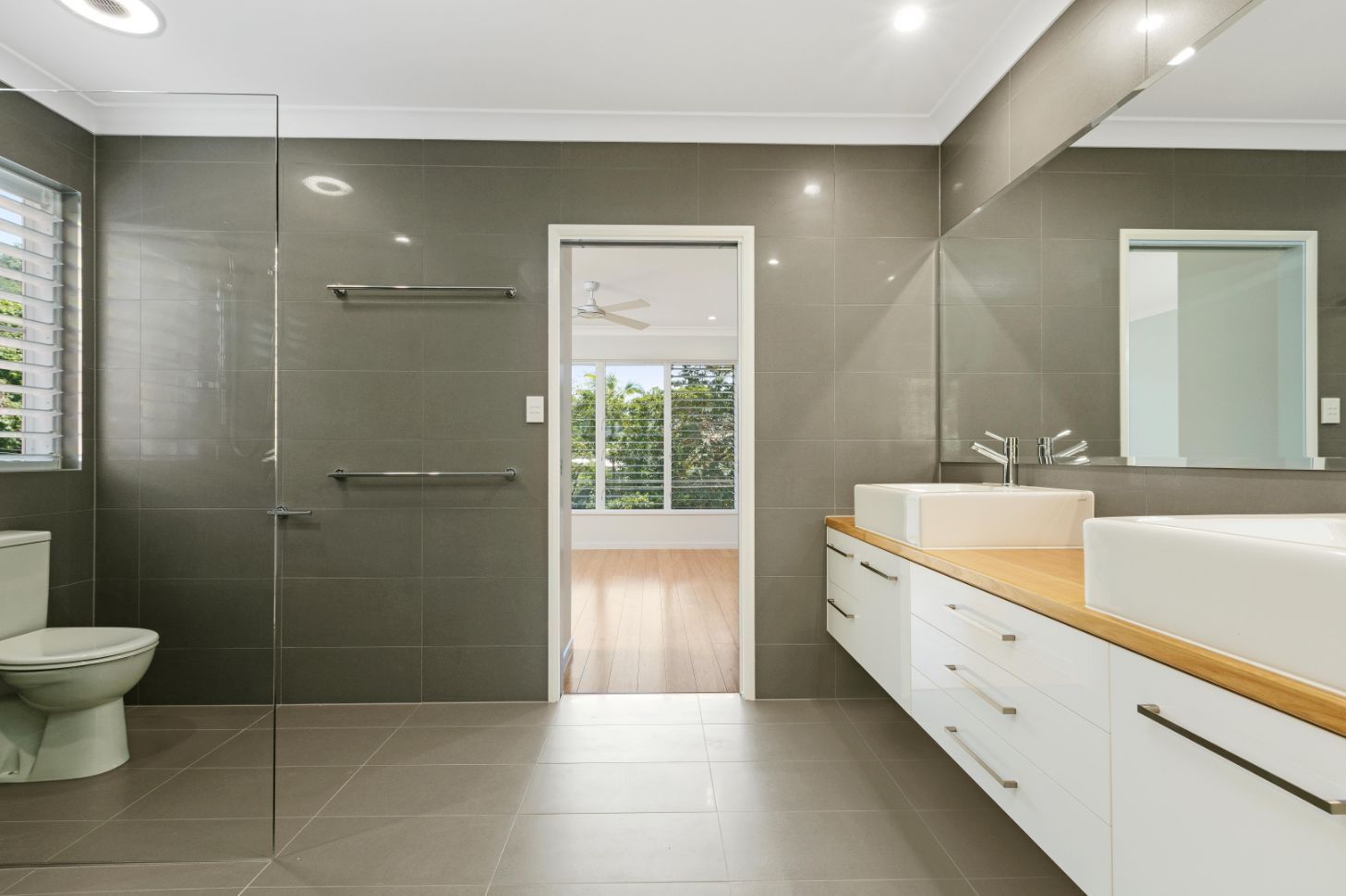 A Bathroom With a Toilet, Sink and Mirror — Ashlee Jones Homes in Gordonvale, QLD