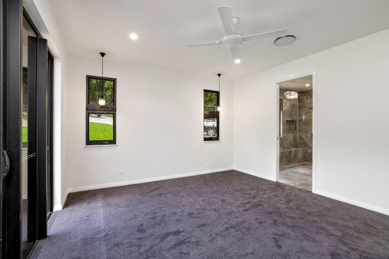 An Empty Room With a Ceiling Fan and a Carpeted Floor — Ashlee Jones Homes in Gordonvale, QLD