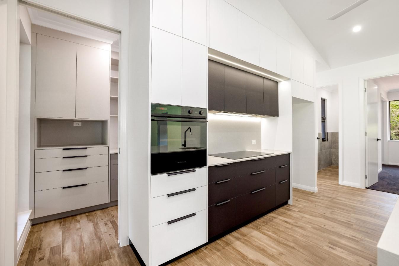 A Kitchen With White Cabinets and Black Drawers and a Stove — Ashlee Jones Homes in Gordonvale, QLD