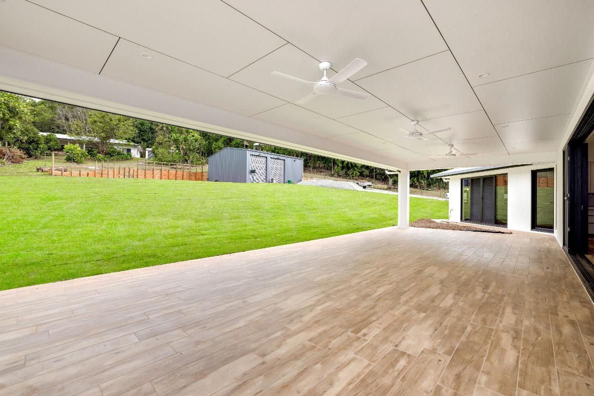 A Large Patio With a Ceiling Fan and a View of a Grassy Field — Ashlee Jones Homes in Gordonvale, QLD