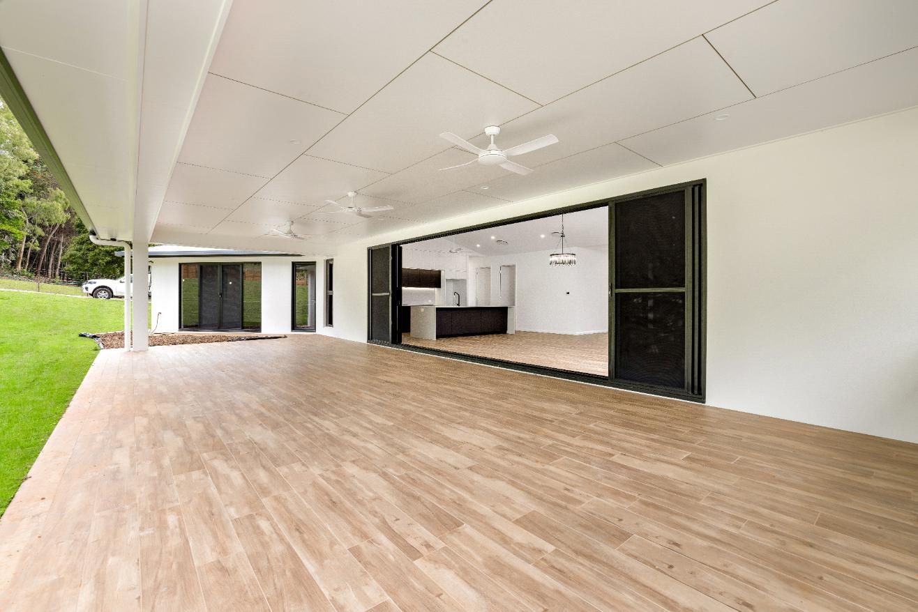 A Large Empty Room with A Wooden Floor and A Ceiling Fan — Ashlee Jones Homes in Gordonvale, QLD