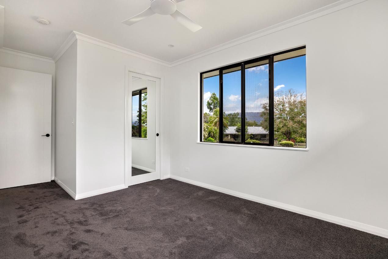 An Empty Bedroom With a Large Window and a Ceiling Fan — Ashlee Jones Homes in Gordonvale, QLD
