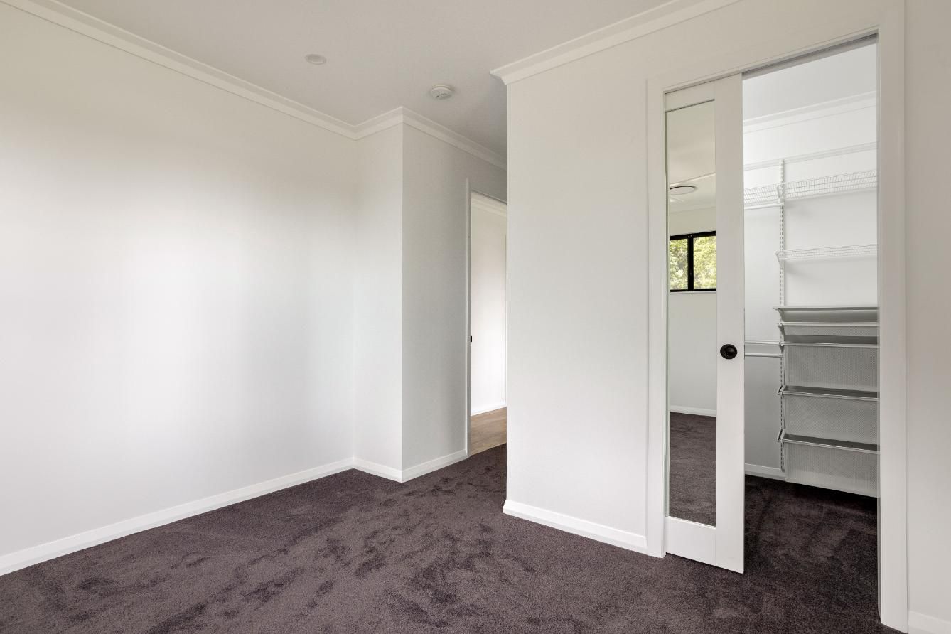 An Empty Bedroom With a Mirrored Door and a Walk in Closet — Ashlee Jones Homes in Gordonvale, QLD