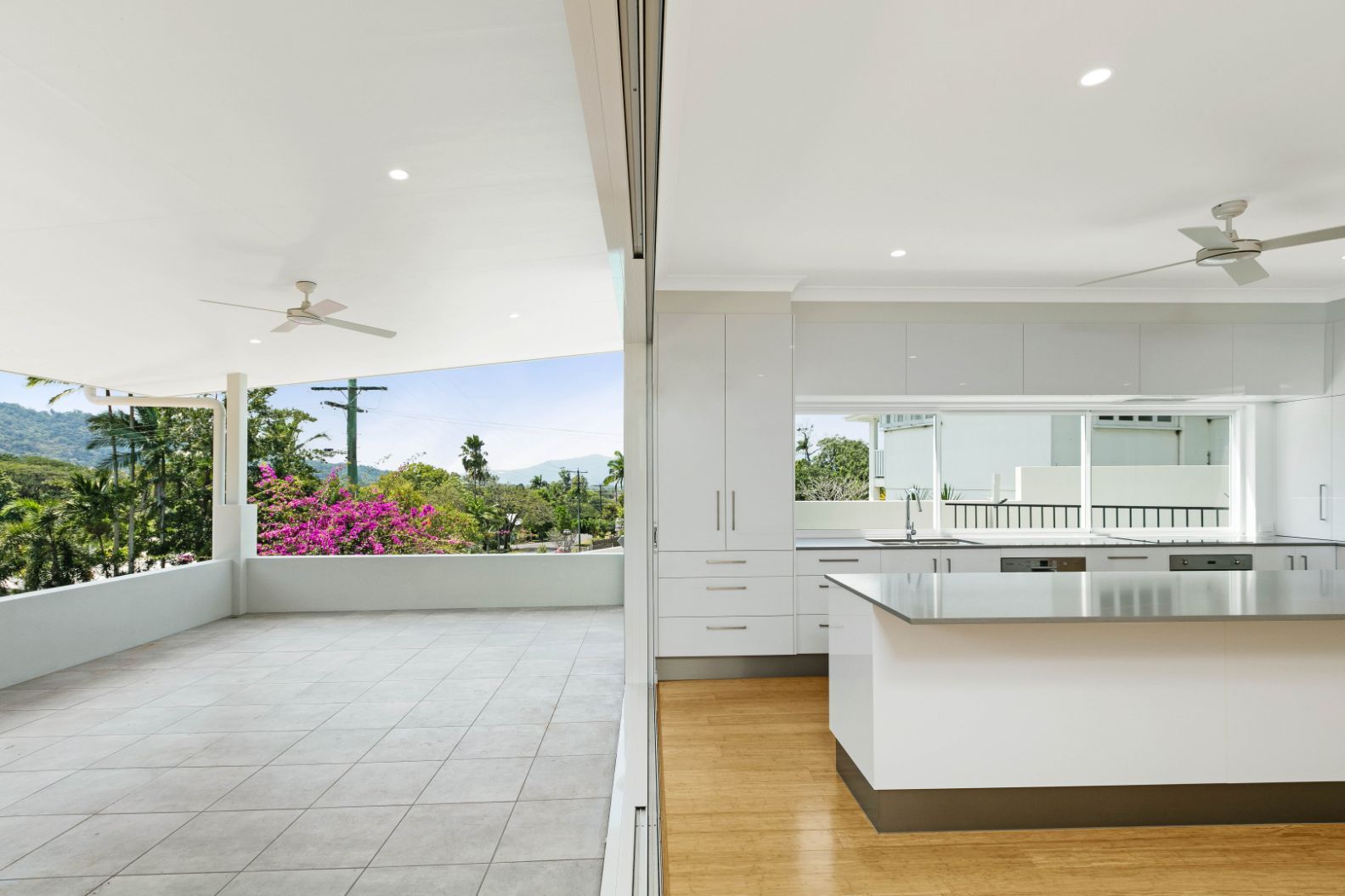 A Kitchen With a Large Island and a Sliding Glass Door Leading to a Balcony — Ashlee Jones Homes in Gordonvale, QLD