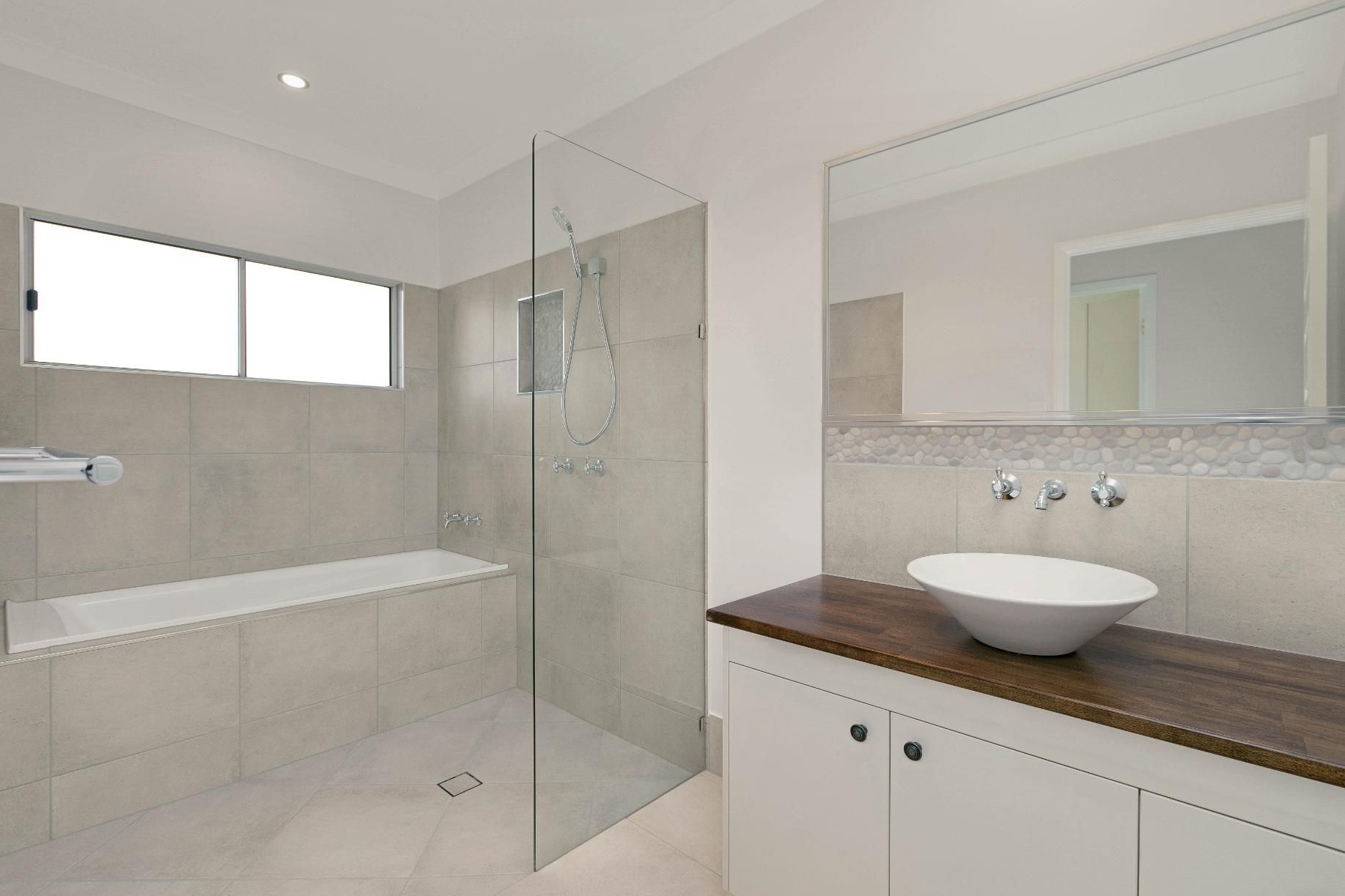 A Bathroom With a Sink, Tub, Shower and Mirror — Ashlee Jones Homes in Gordonvale, QLD