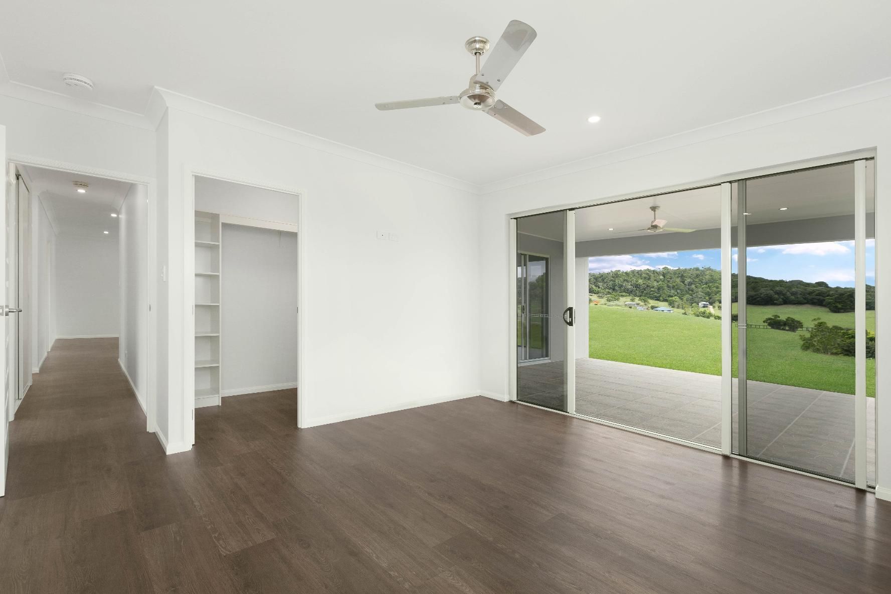 An Empty Living Room With a Ceiling Fan and Sliding Glass Doors — Ashlee Jones Homes in Gordonvale, QLD