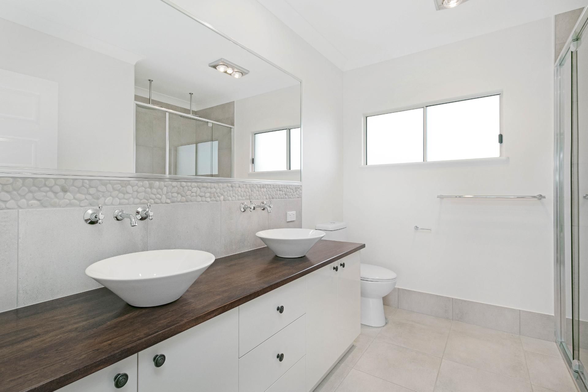 A Bathroom With Two Sinks and a Toilet — Ashlee Jones Homes in Gordonvale, QLD