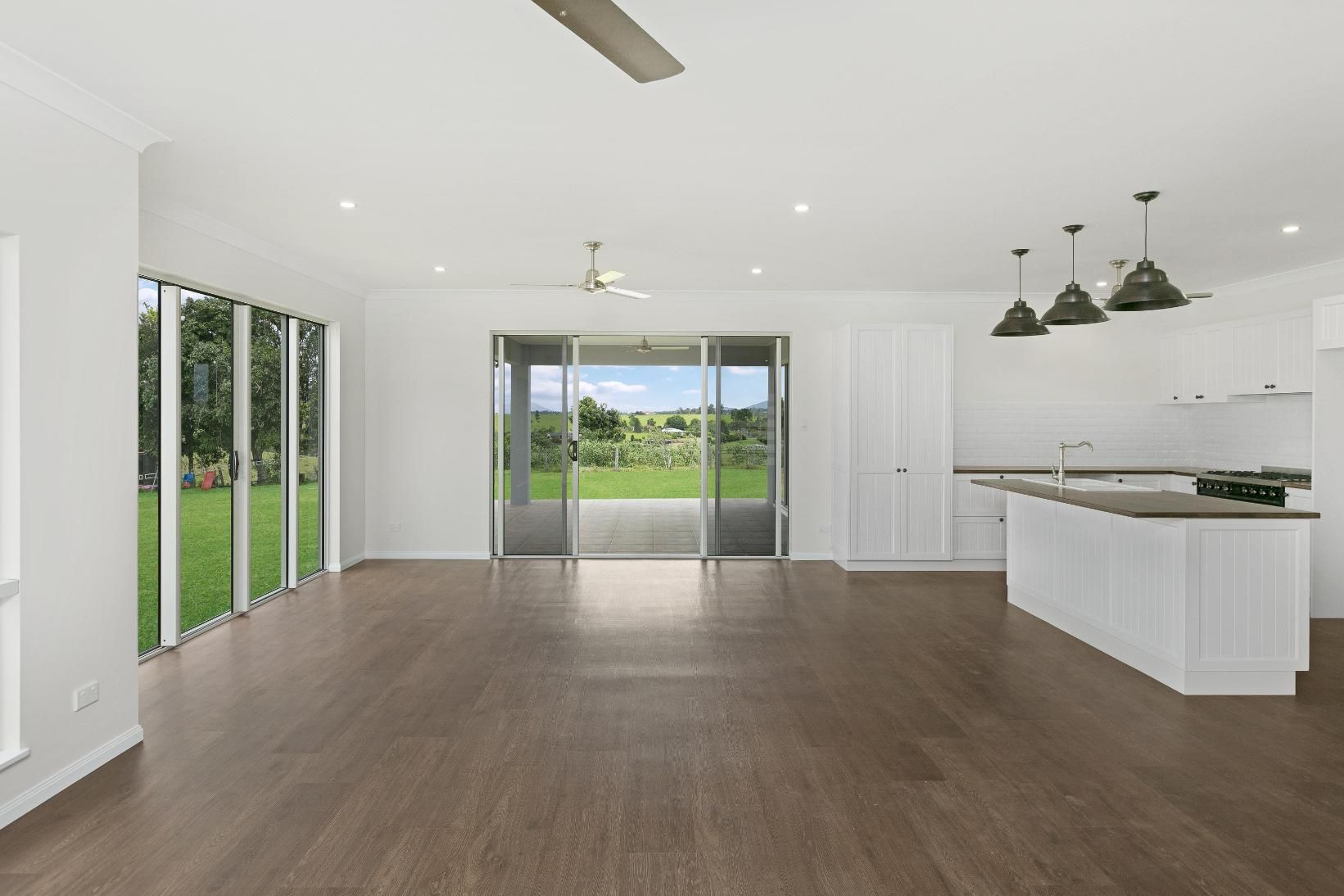 An Empty Kitchen With Hardwood Floors and a Ceiling Fan — Ashlee Jones Homes in Gordonvale, QLD