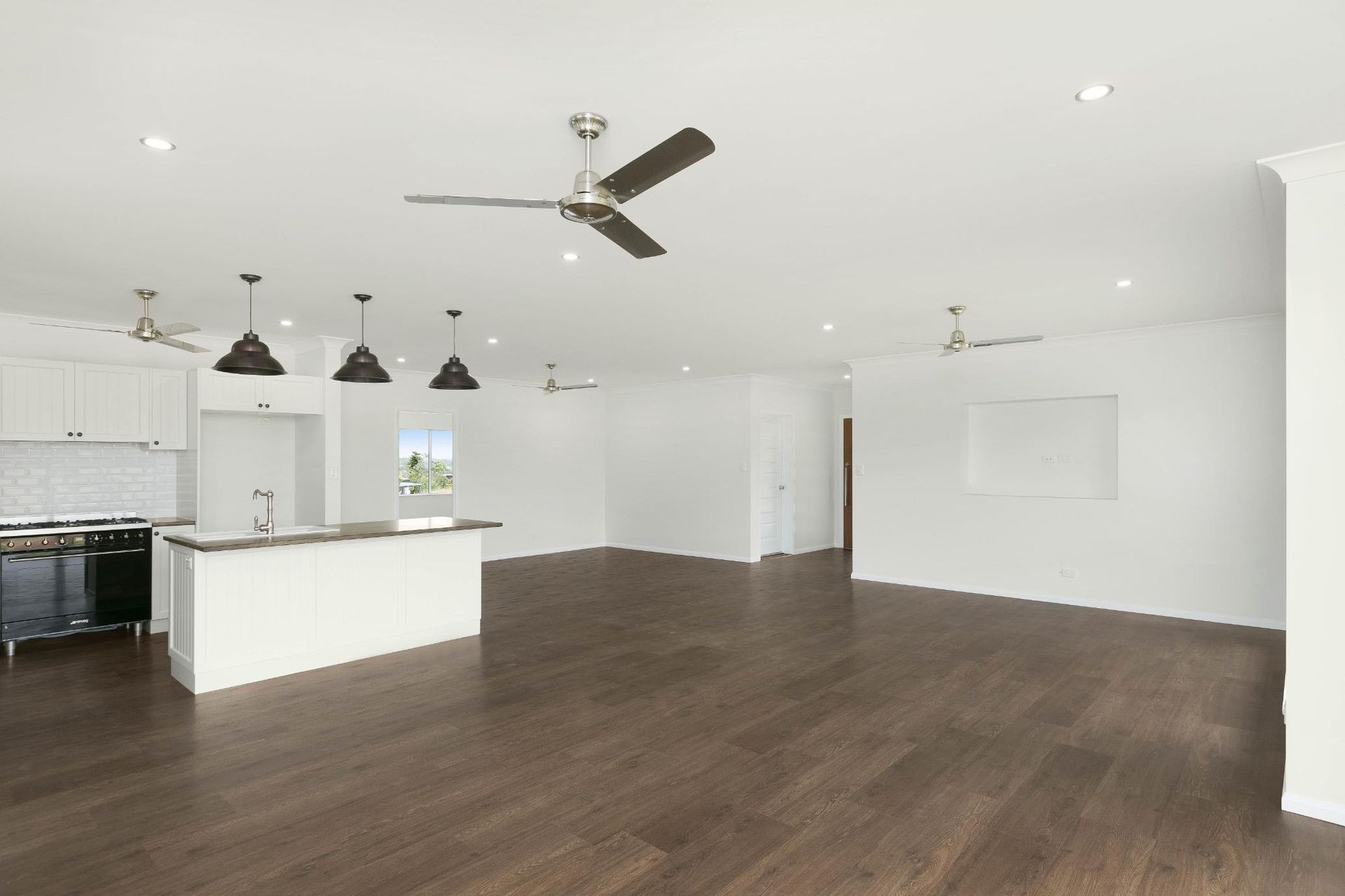 A Large Empty Room With a Ceiling Fan and Wooden Floors — Ashlee Jones Homes in Gordonvale, QLD