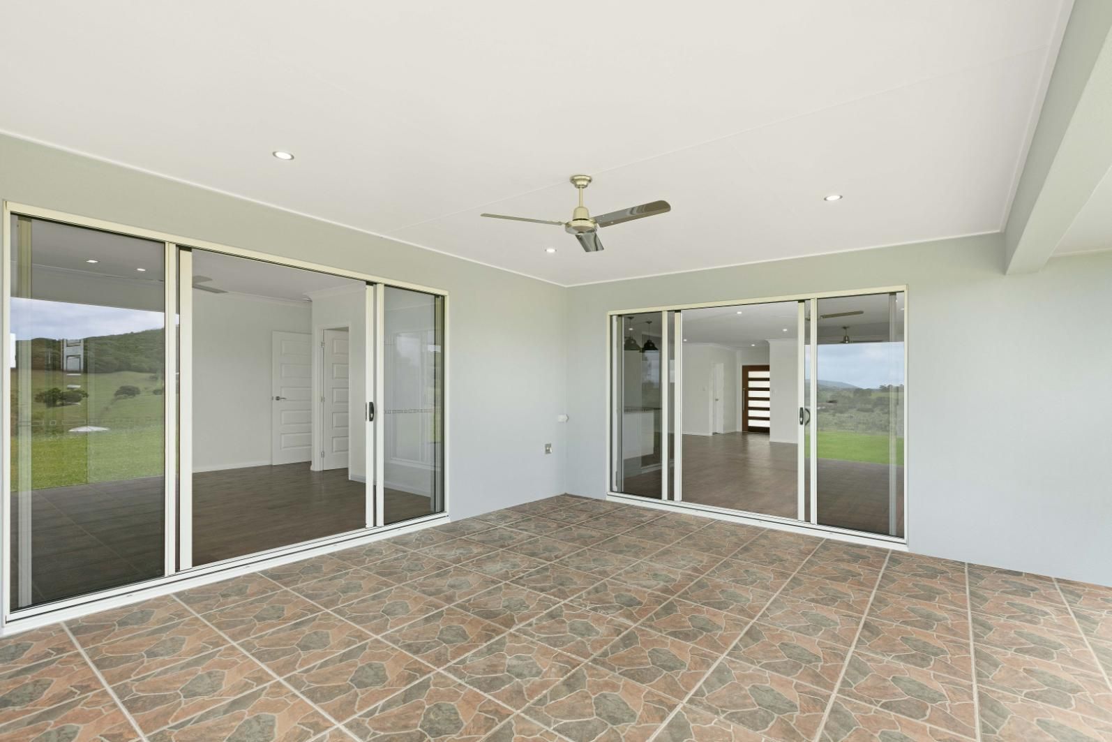 An Empty Patio With Sliding Glass Doors and a Ceiling Fan — Ashlee Jones Homes in Gordonvale, QLD