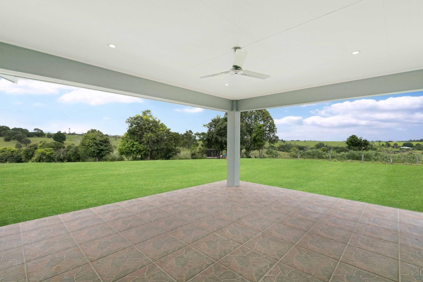 An Empty Patio With a Ceiling Fan and a View of a Grassy Field — Ashlee Jones Homes in Gordonvale, QLD