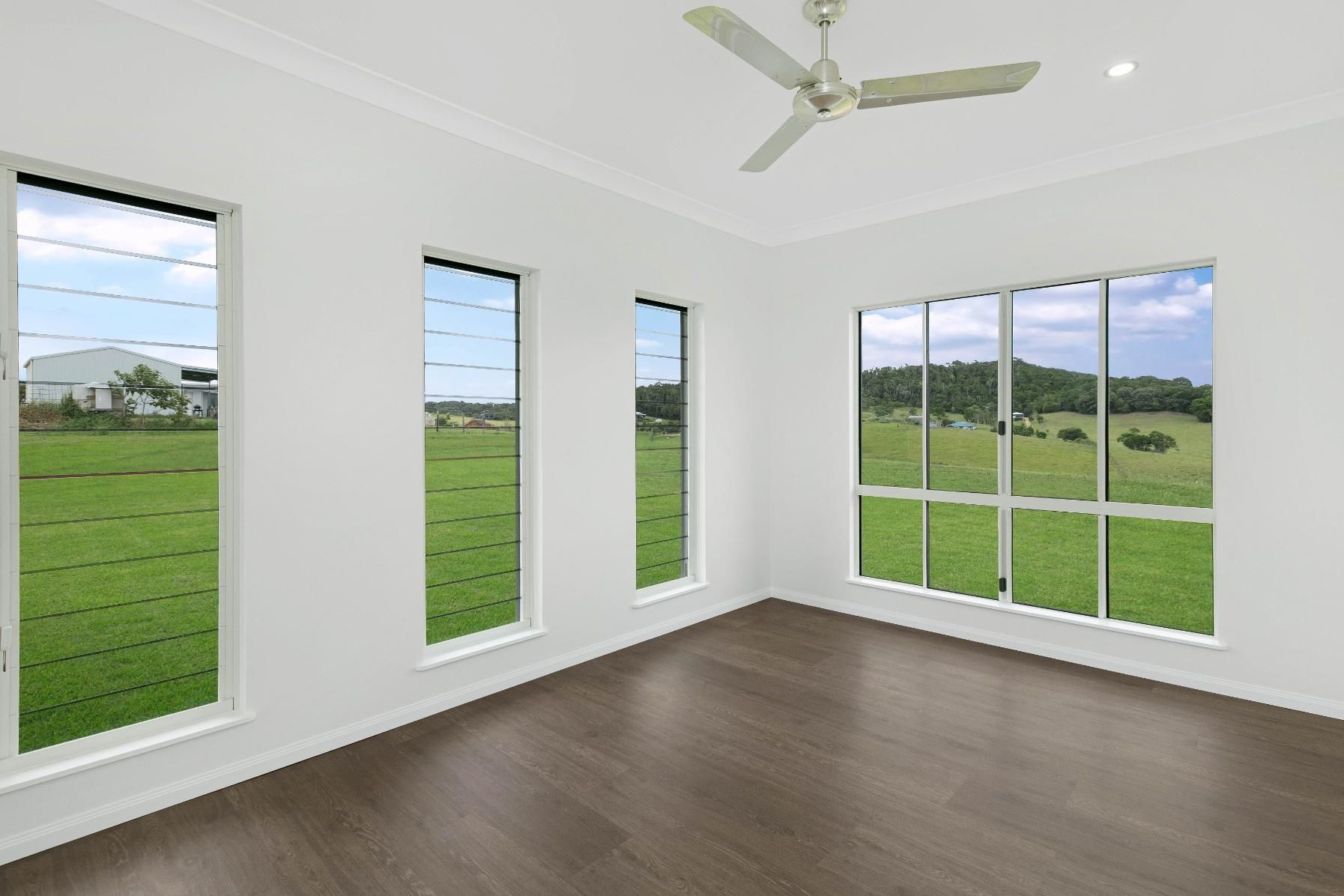 An Empty Room With a Ceiling Fan and Lots of Windows — Ashlee Jones Homes in Gordonvale, QLD
