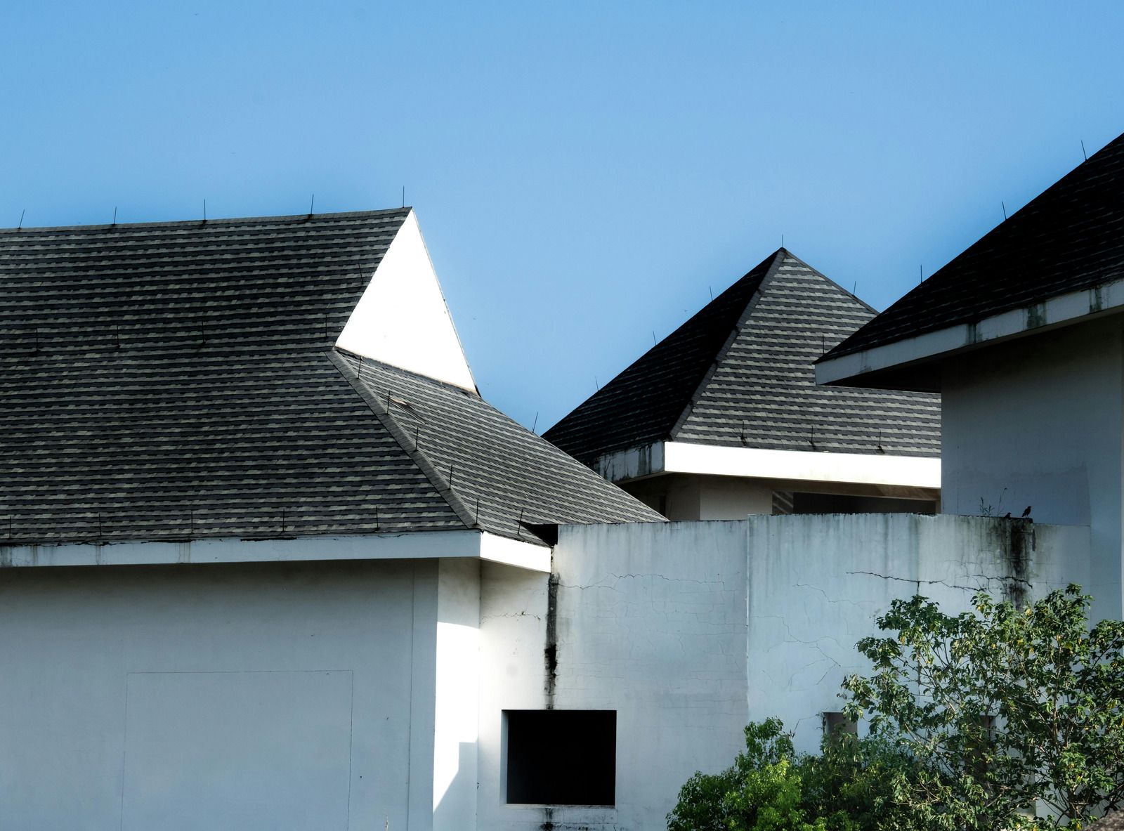 White buildings with dark, textured roofs against a clear blue sky.