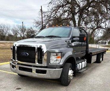 A flatbed tow truck is parked in a parking lot.