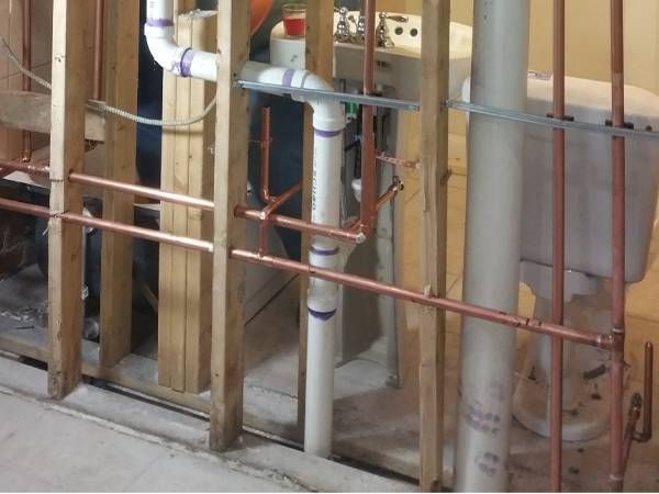 A bathroom under construction with copper pipes and a toilet.
