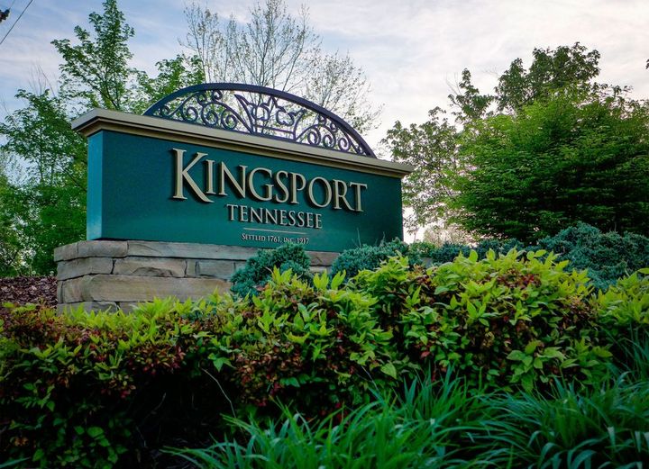 A sign for kingsport tennessee is surrounded by greenery and trees.
